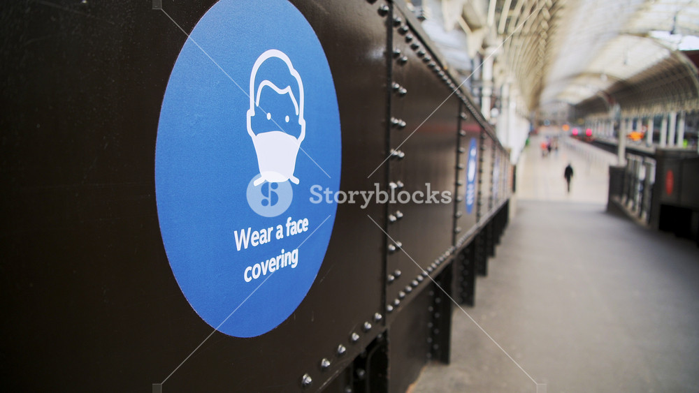 Coronavirus Covid-19 information sign saying wear a face covering mask at Paddington Train Station in London when public transport was