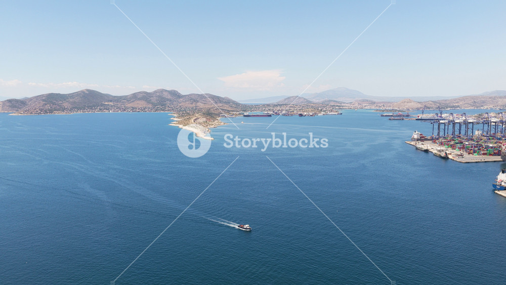 Beautiful aerial panorama of the port of piraeus in greece, showing the busy container terminal, cargo ships, and the deep blue sea of the saronic gulf under a clear summer sky