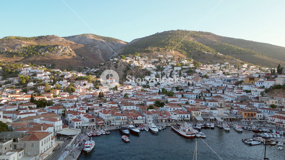 Aerial footage of Hydra port, Greece. Scenic view of boats moored at the harbor with traditional stone buildings.