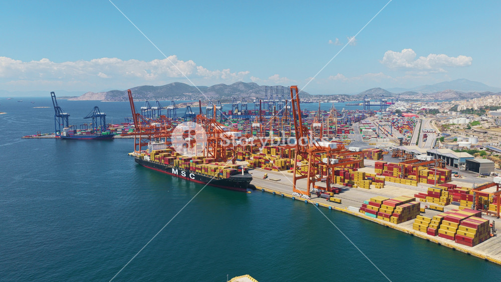 Beautiful aerial panorama of the port of piraeus in greece, showing the busy container terminal, cargo ships, and the deep blue sea of the saronic gulf under a clear summer sky
