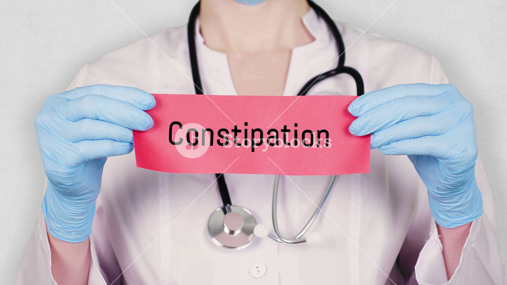 closeup, hands in blue medical gloves hold and tear red paper card with an inscription constipation. doctor dressed in white medical uniform, has a stethoscope.