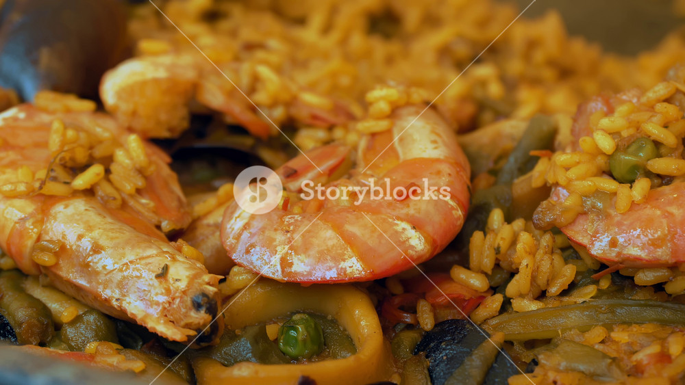 Close up of seafood paella cooking over open fire in large frying pan. Combination of fresh mussels, squid and prawns for outdoor catering.