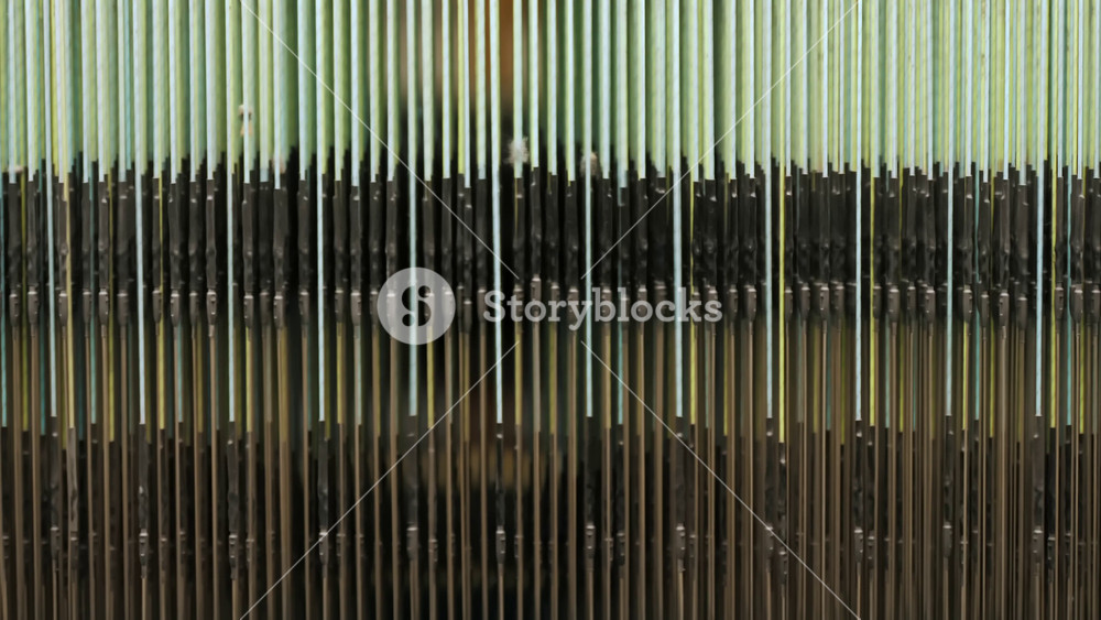 Detailed view of industrial weaving machinery parts in operation. Automated textile technology manufacturing fabric at a plant.