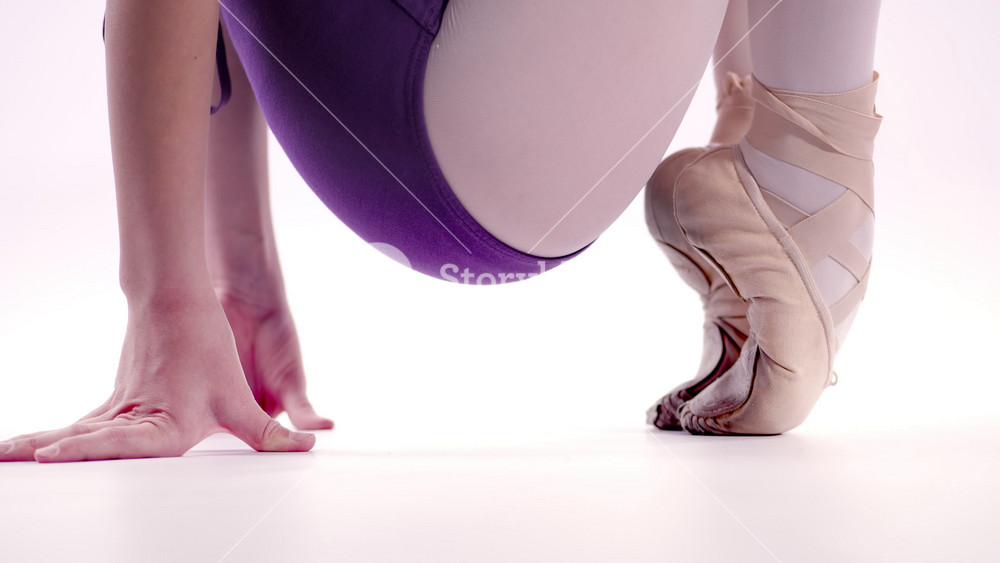 Closeup of ballet feet with contrast between barefoot and foot in beige pointe shoes. Ballet footwear and technique detail.