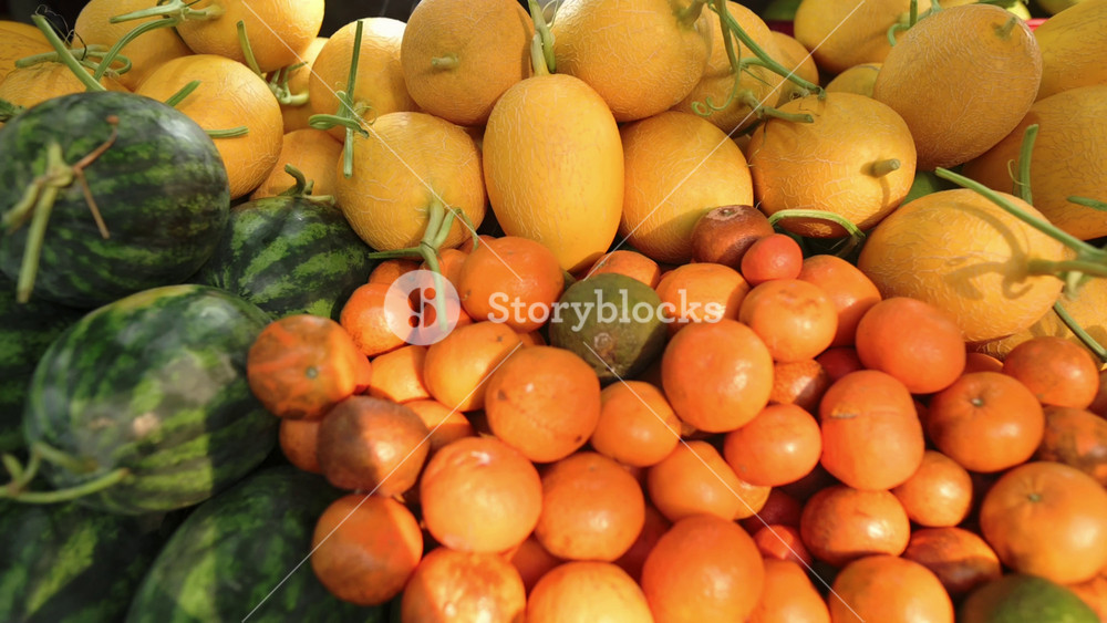Colorful Display Of Fresh Fruits And Vegetables. Vibrant Market Scene With Ripe Oranges And Melons On Stand. Energetic Marketplace
