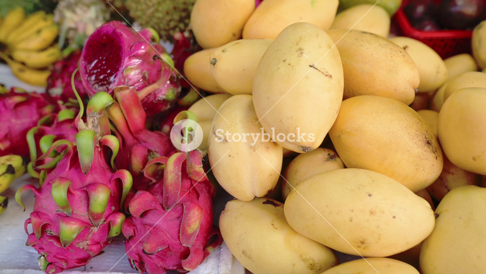 Colorful Dragon Fruit Mangoes Vietnam Street Market Closeup Of Pitaya And Ripe Mango Pile, Bananas At Edge, Vivid Pink Interior Of Sliced