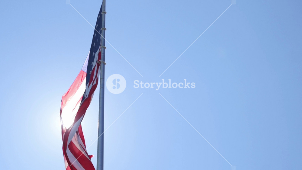 Bright sun highlights American flag, Sunlit outline of national flag with flare, Silhouette of United States banner illuminated intensely