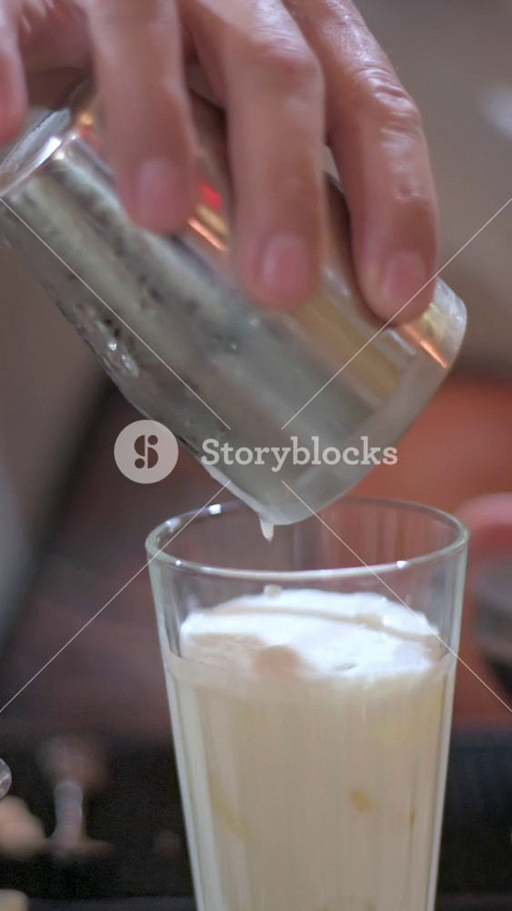 Vertical screen Gentle Cascade Of Coconut Foam Fills Glass. Coconut Foam Cascades Smoothly Into Icefilled Tall Glass. Delicately Pouring