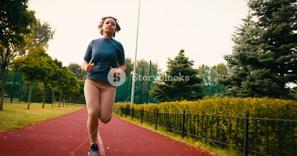 Young Sporty Woman Runner is Training in Morning in Public Park. Fitness Girl is Jogging outdoor. Concept of Workout Running and Healthy