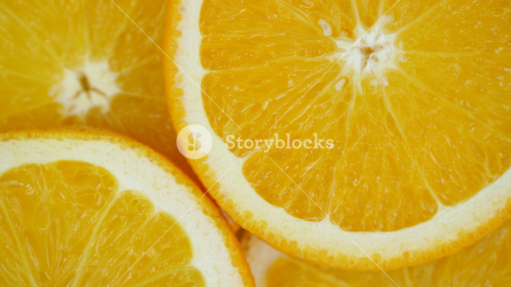 Fresh slices of orange citrus lie exposed. Bright juicy flesh contrasts with textured peel. Natural colors reflect healthy food and seasonal
