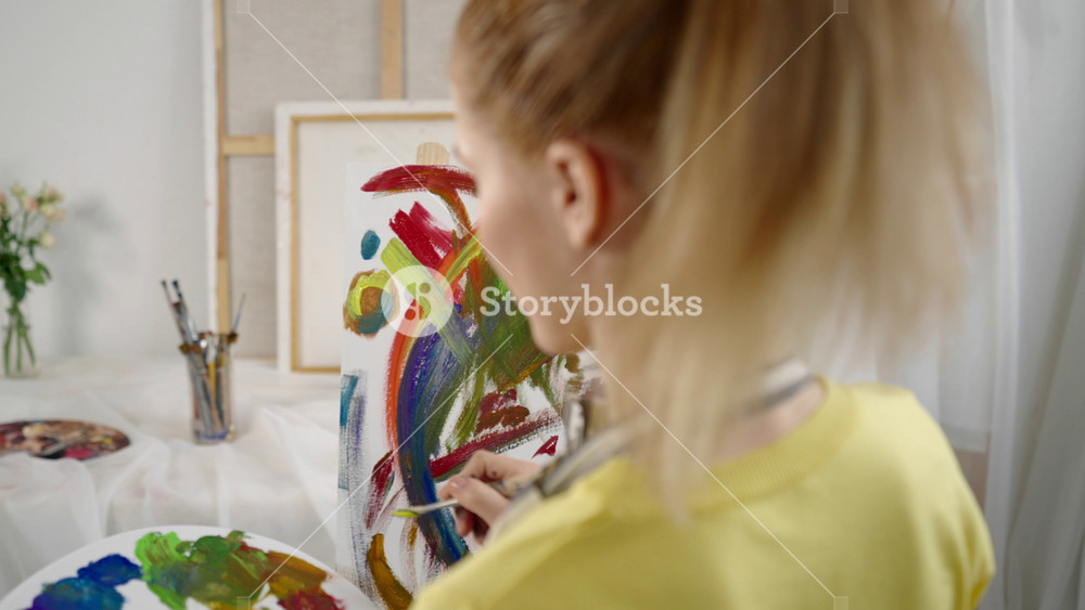 Female student of art school drawing abstract picture on easel in workshop. Talented woman artist working in art studio, of professional