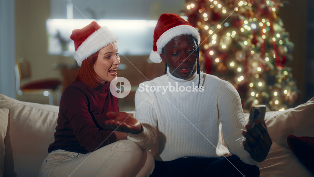 Celebration of Christmas, biracial couple calling by smartphone online, portrait. Happiness and joy in winter holidays, multiethnic people