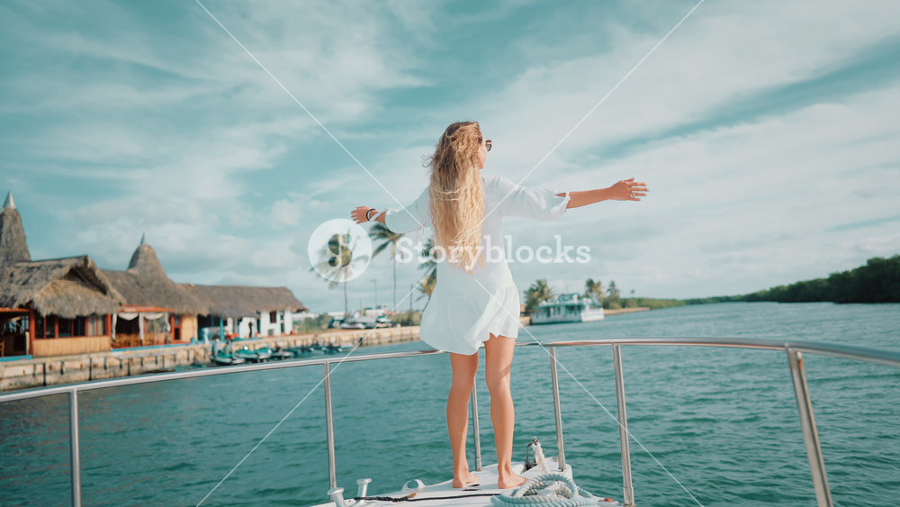 Yachting near islands in pacific ocean in summer, beautiful blonde woman on boat . slender lady with long hair enjoying sunny day on