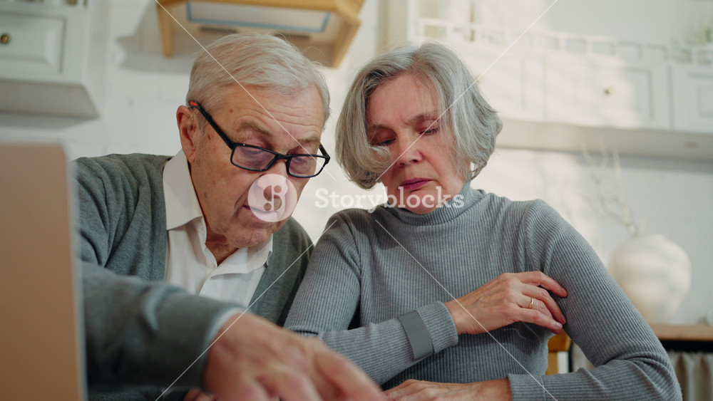 Frustrated old woman and husband viewing paper and looking for info in laptop. Senior people examining bank or medical papers, financial or