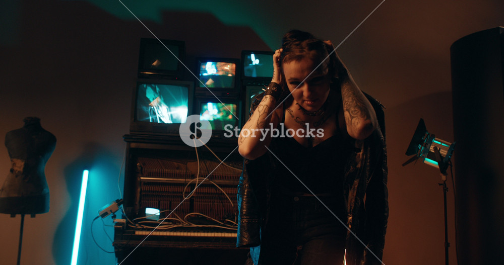 Crazy woman standing alone in dark room with few TV displays, psychosis. Portrait of young adult brunette lady in alternative style, rock