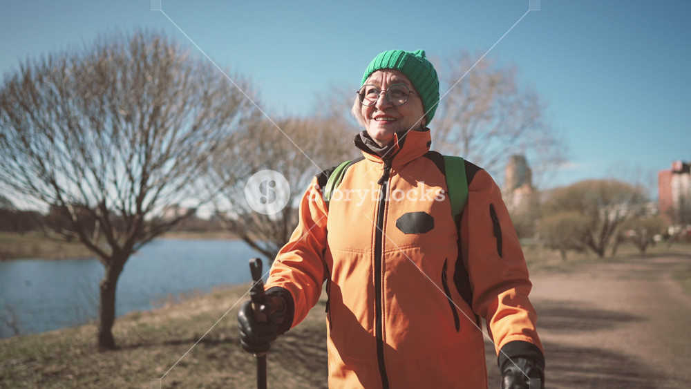 Portrait of happy old lady with poles for nordic walking in park in motion. Active lifestyle and sport activity for stay healthy and