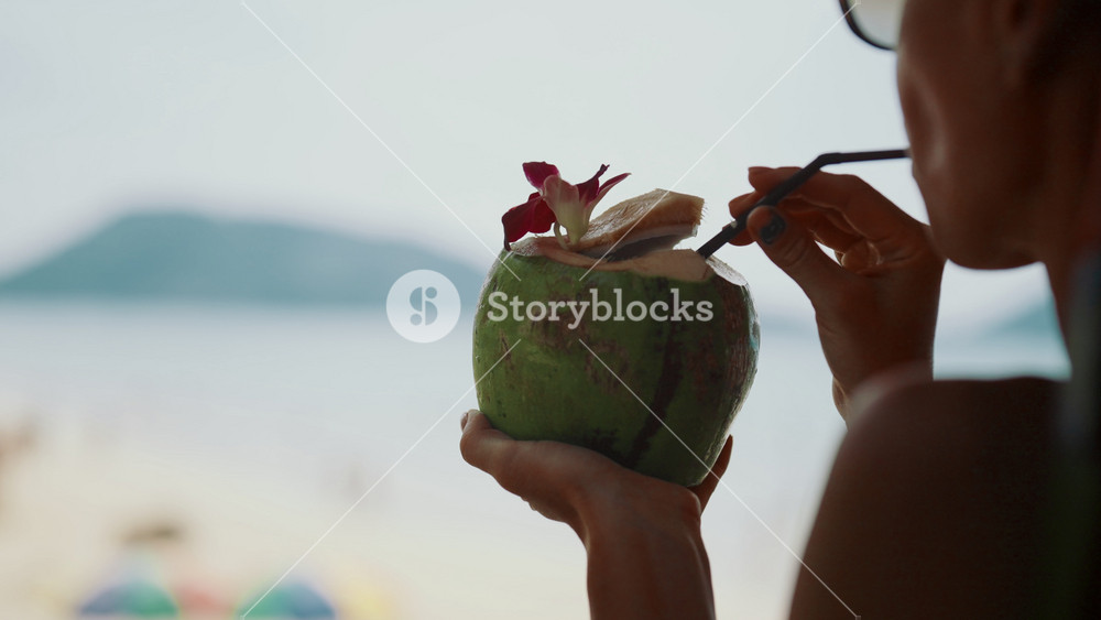 Delicious fresh coconut cocktail in hands of woman vacationer, enjoy summer trip. Freshness and quench thirst, lady resting in tropical