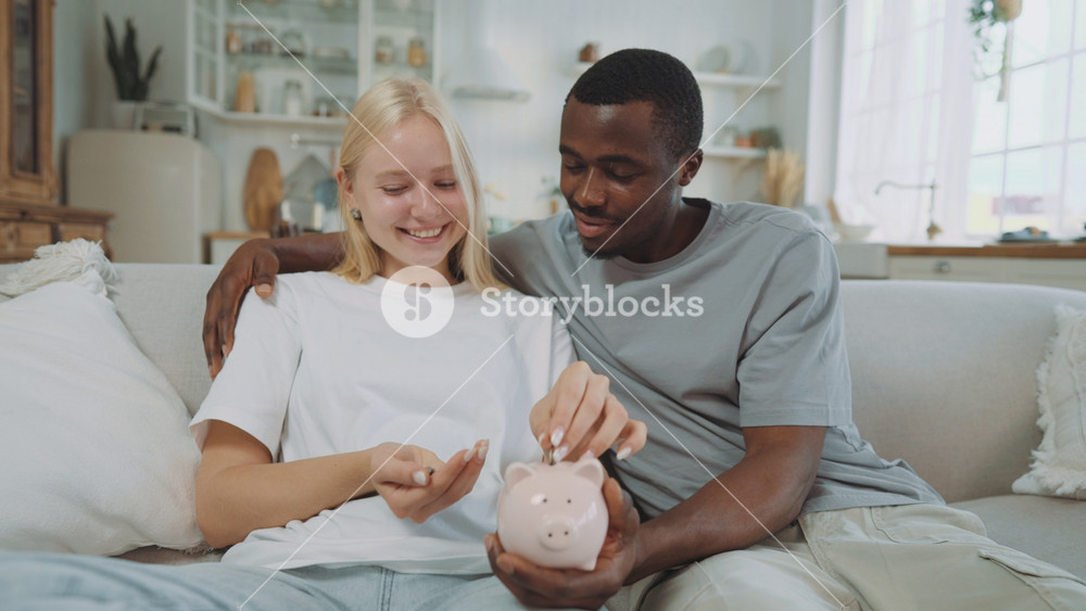 Young students pair saving money for future, lady putting coins into piggy bank. Portrait of happy blonde woman and african american man