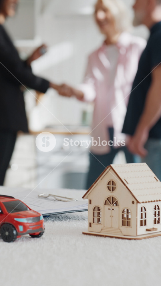 Realtor and happy homeowners shaking hands and giving keys of new apartment. Successful deal of buy and sale properties, professional real