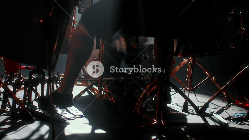 Legs of drummer on stage during rock gig, details and close-up, play music. Contemporary music concert, male musician punching drums