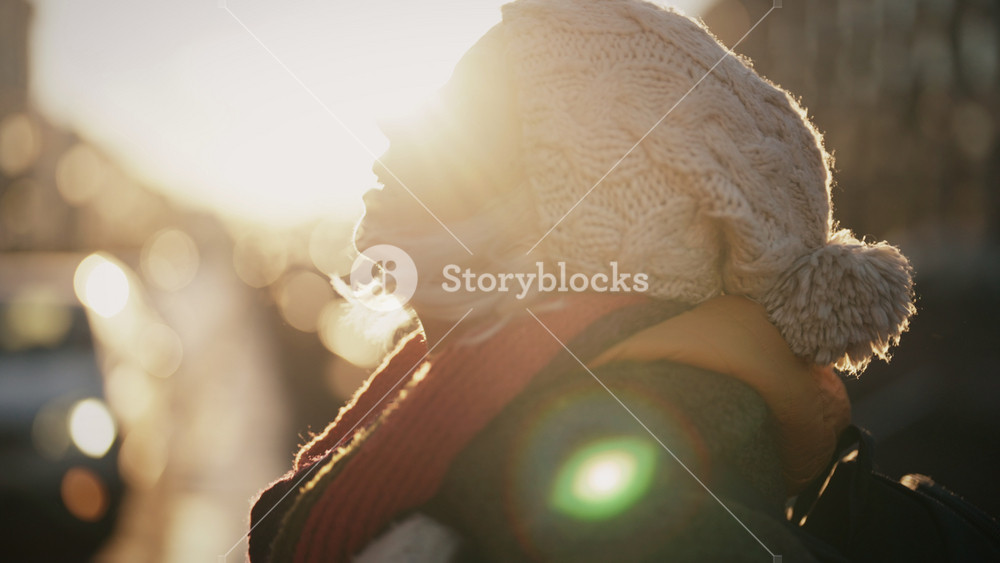 Winter in city, portrait of middle-aged woman in knitted hat and mittens outdoor . Walk in downtown in cold day, beautiful sunlight