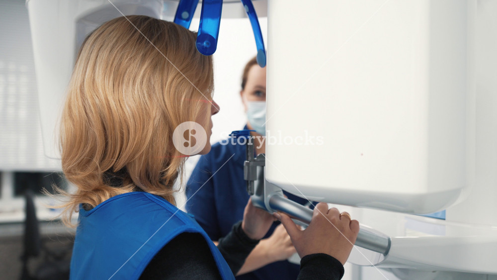 Female dentist doing tomography and radiography in modern dental clinic. Young woman patient visiting stomatology clinic, high-end equipment