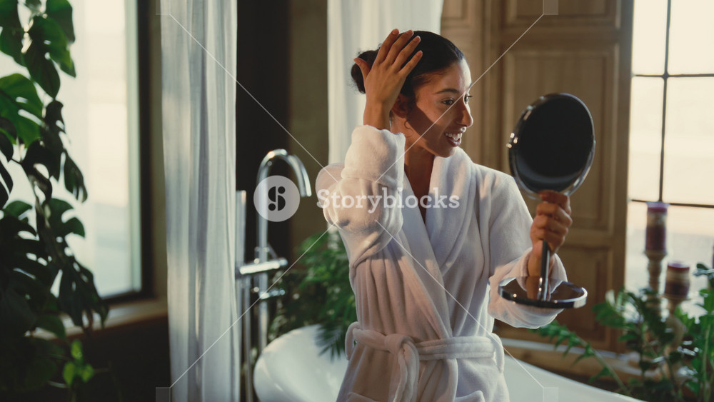 Daily morning routine, woman admiring her beautiful skin after treatments. Portrait of happy Arab lady admiring her face in small mirror in