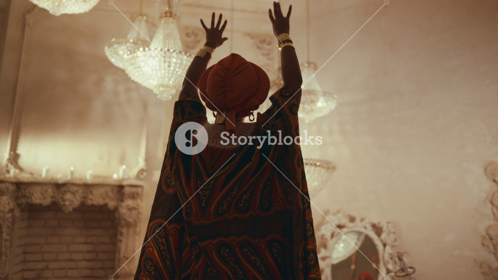 Beautiful african woman in ethnic dress and turban dancing on sand in studio. Culture and traditions of african people, trip to african and
