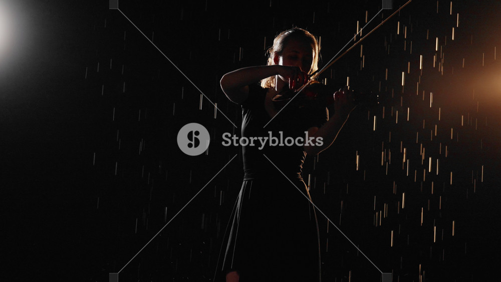 Talented female violinist playing music in night rain, medium shot. Portrait of slender fragile lady performing melody by violin, enjoy