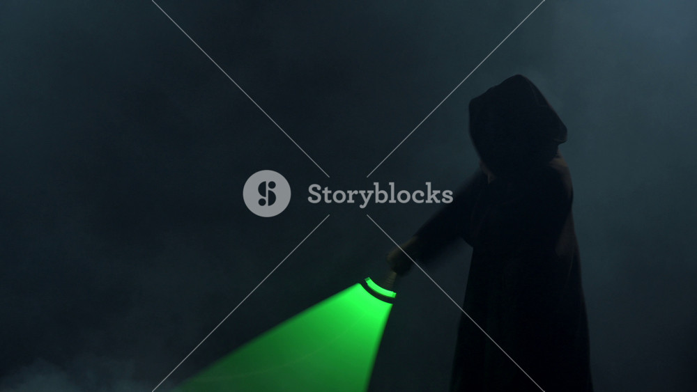 Young man in cosplay costume with lightsaber battle on black background in smoke and rain, 4k slow motion video filmed on 8k camera nikon z9