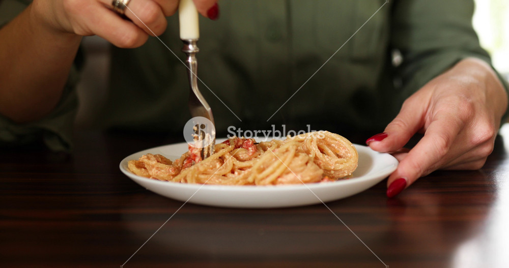 Woman eating Italian dish with baked feta cheese tomatoes and spaghetti at kitchen at home, Trending viral recipe FetaPasta.