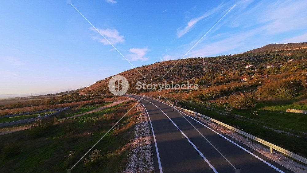 Cyclist on winding mountain road at sunset surrounded by vibrant autumn foliage ideal for travel adventure outdoor fitness nature and
