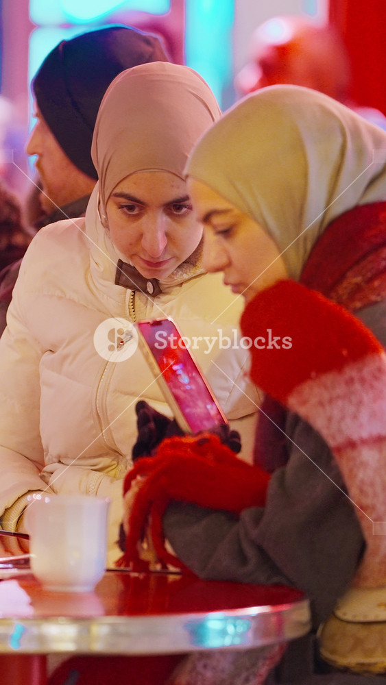 Paris, France - December 20, 2025: People sitting at tables of a cozy Parisian cafe in the evening. A traditional Parisian cafe with tables