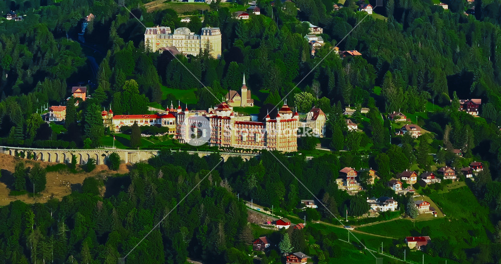 Establishing shot of Switzerland. Aerial view of the green meadows of Switzerland, with the Alps and clouds in the background