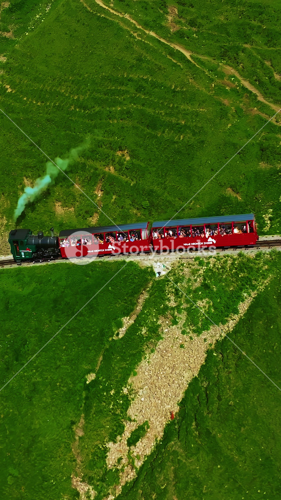 Aerial video of the red train traversing the viaduct. The Swiss Express travels through the green meadows and mountains of Switzerland