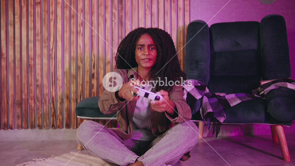 A young woman happily plays video games at home, in her stylish, colorful living room that enhances her overall gaming experience