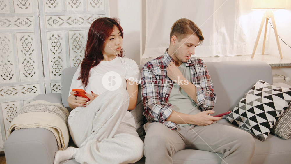 An angry, jealous asian wife suspects her husband of infidelity. woman grabbed a smartphone from a man's hands, reads his private messages