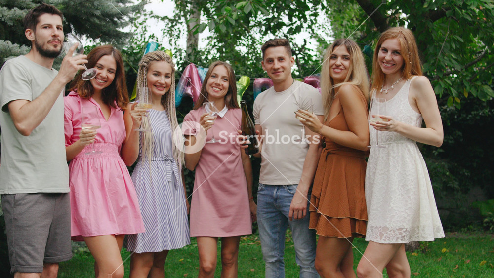 A joyful group of friends in festive hats raises their champagne sharing heartfelt toasts and wishes and lookong on camera