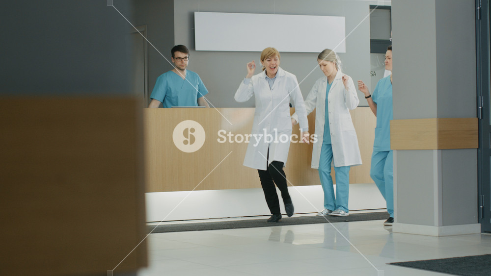 Team of Doctors, Nurses and Assistants Dances After Successful Procedure, They Walk Through the Lobby of the Modern Hospital. Medical Personnel Having Fun.