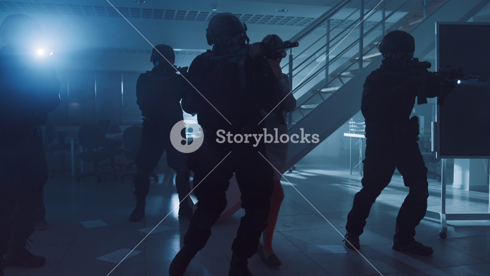 Masked Squad of Armed SWAT Police Officers Rescue a Female Hostage in a Dark Seized Office Building with Desks and Computers. Soldiers with Rifles and Flashlights Move Forwards and Cover Surroundings.