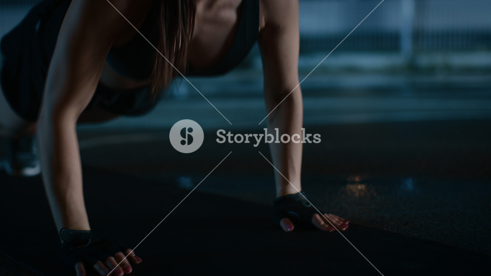Sporty Fitness Girl Doing Push Up Exercises. She is Doing a Workout in a Fenced Outdoor Basketball Court. Night Footage After Rain in a Residential Neighborhood Area.
