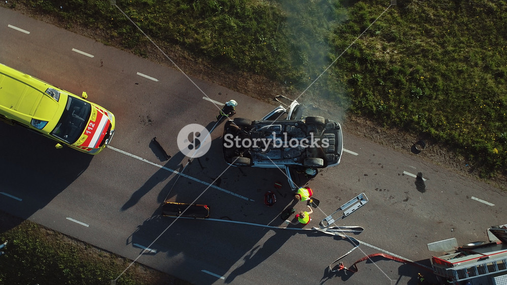 Aerial View: Rescue Team of Firefighters and Paramedics Work on a Car Crash Traffic Accident Scene. Preparing Equipment, First Aid Help. Saving Injured and Trapped People from the Vehicle. Zoom in