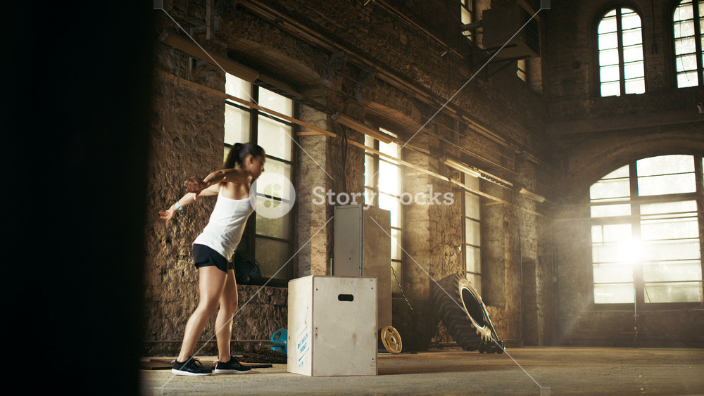 Fit Athletic Woman Does Box Jumps in the Deserted Factory Gym. Intense Exercise is Part of Her Daily Cross Fitness Fitness Training Program.