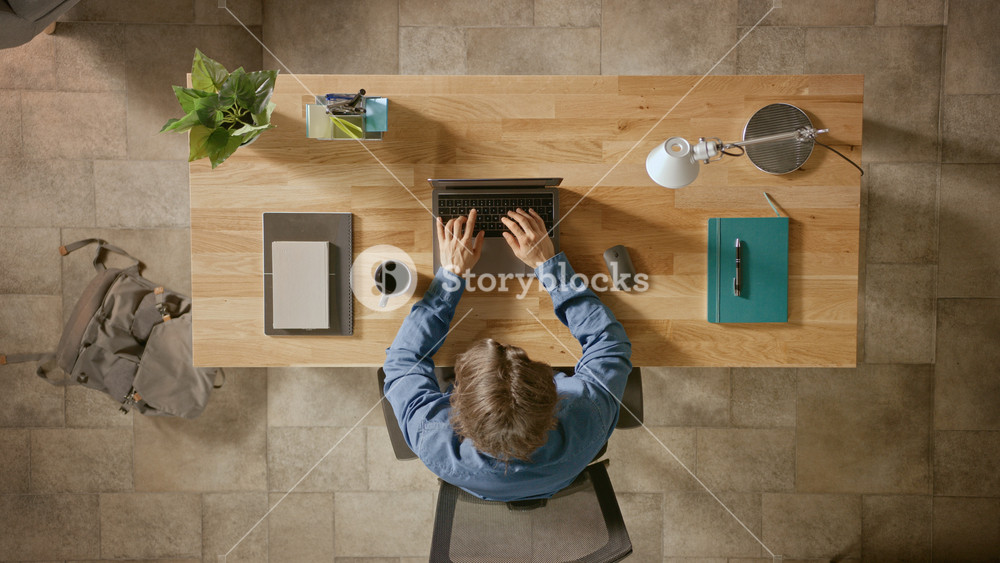 Top View Zoom In Shot: Businessman Sitting at the Wooden Desk Works on a Laptop in his Home Office. He Drinks Coffee, Types, Writes Emails, Surfs the Internet, Designs Software, Online Shopping