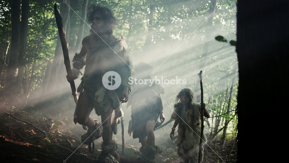 Tribe of Hunter-Gatherers Wearing Animal Skin Holding Stone Tipped Tools, Explore Prehistoric Forest in a Hunt for Animal Prey. Neanderthal Family Hunting in the Jungle or Migrating for Better Land