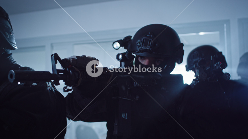 Close Up Portraits of Masked Squad of Armed SWAT Police Officers Storm a Dark Seized Office Building with Desks and Computers. Soldiers with Rifles and Flashlights Move Forward and Cover Surroundings.