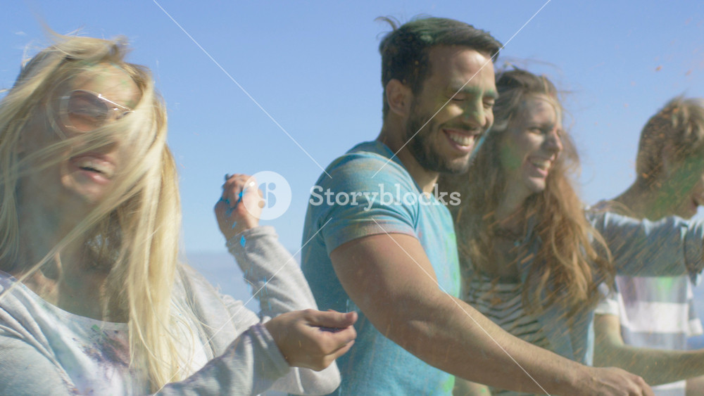 Multi-Ethnic Group of Young People Throw Colorful Powder at Each other in Celebration of Holi Festival. They Have Enormous Fun on this Clear Day by the Sea.