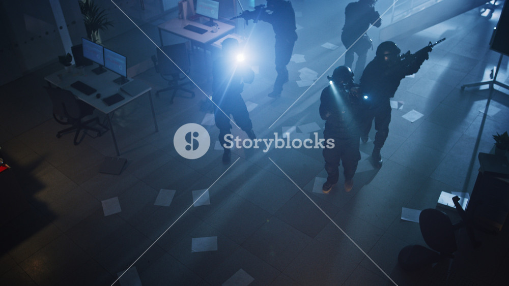 Masked Squad of Armed SWAT Police Officers Storm a Dark Seized Office Building with Desks and Computers. Soldiers with Rifles and Flashlights Move Forwards and Cover Surroundings. Above-view Camera.