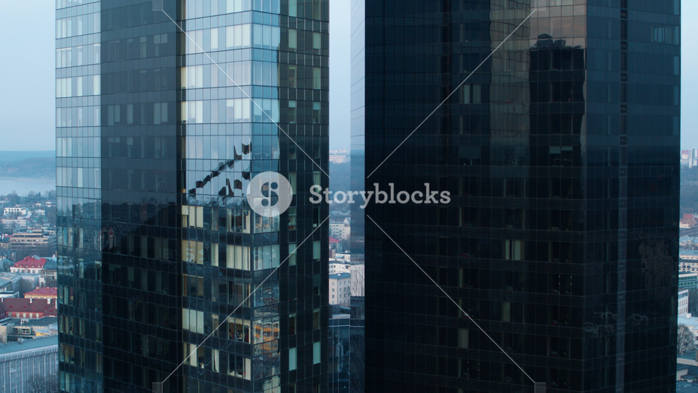 Descending Aerial Shot of the Luxury Residential Skyscrapers and Business District. Big, Beautiful Buildings with Dark Mirror Looking Windows Reflecting Neighbouring Skyscrapers, Roads and Sky.
