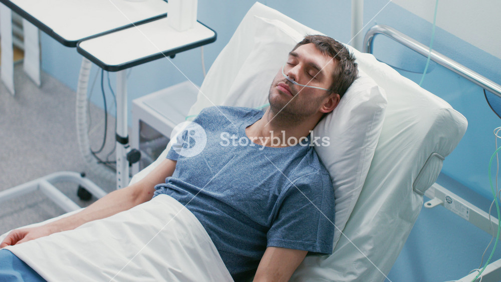 In the Hospital Sick Male Patient Sleeps on the Bed, He's Wearing Nasal Cannula. Nurse Enters and Checks His Drop Counter, Increases Dose of Pain Killer.